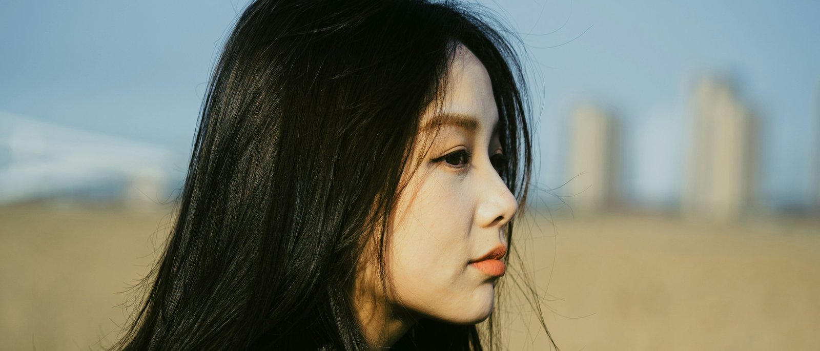 바람에 머릿결을 맡긴 옆모습 — 두상의 곡선과 헤어라인이 드러난다